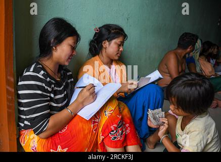 Imphal, India. 14 luglio 2023. Le donne si spacciano per passare il tempo in un campo di soccorso. Il campo di soccorso sta ospitando i residenti della comunità Meitei, le cui case sono state raso al suolo all'inizio della crisi comunitaria in corso. Più di 50.000 persone sfollate per violenza a Manipur sono attualmente ospitate in 349 campi di soccorso. (Foto di Biplov Bhuyan/SOPA Images/Sipa USA) credito: SIPA USA/Alamy Live News Foto Stock