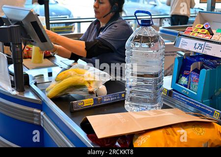 Cassiere al supermercato con prezzi articoli con cibo e bottiglia d'acqua sul nastro trasportatore Foto Stock