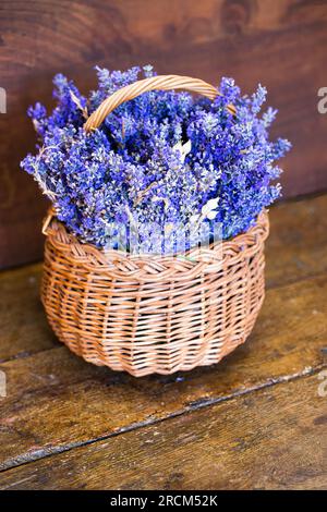 Lavanda fresca (Lavandula angustifolia) in un cestino di vimini su un tavolo di legno Foto Stock