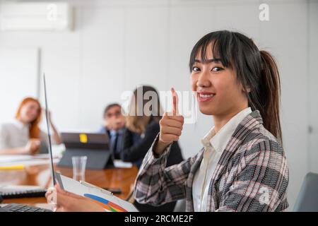 Una donna d'affari con il pollice in ufficio al lavoro, gruppo multietnico Foto Stock