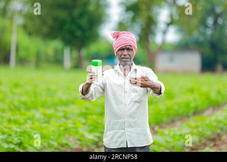 Indiano Happy Farmer tenendo in mano bottiglia vuota, Happy Farmer che mostra bottiglia bianca Foto Stock