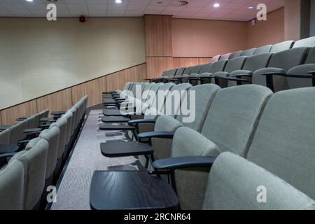 grandi file di sedie vuote con piccoli tavoli laterali in un centro conferenze Foto Stock