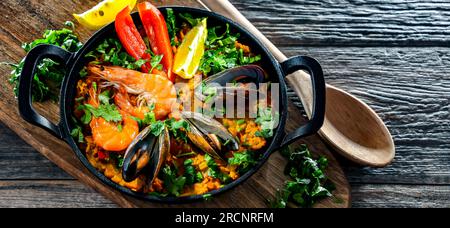 Paella di pesce servita in una padella di ghisa. Foto Stock