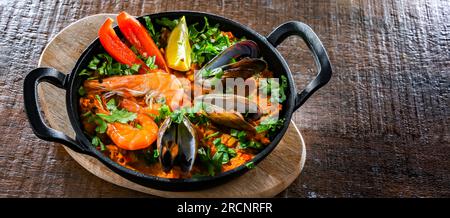 Paella di pesce servita in una padella di ghisa. Foto Stock