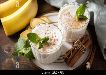 Menu Detox (disintossicazione). Frullato alla banana con cannella in bicchiere su sfondo di legno. Foto Stock