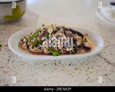 Cibo thailandese, insalata piccante di maiale macinato (Larb Moo) su piatto bianco. Foto Stock