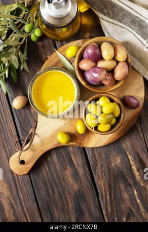 Olive appena raccolte frutti di bosco in ciotole di legno e olio pressato servito su vecchie tavole di legno. Vista dall'alto. Copia spazio. Foto Stock