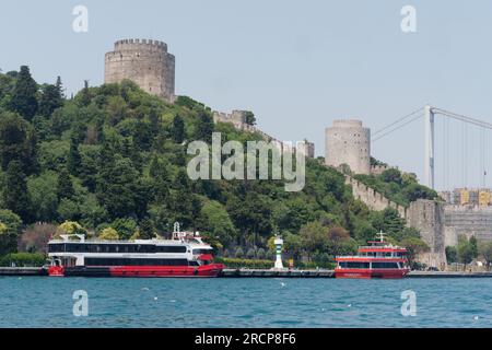 Fortezza di Rumeli su una collina con traghetti passeggeri sul lungomare del Bosforo e sul ponte Fatih Sultan Mehmet, Istanbul, Turchia Foto Stock