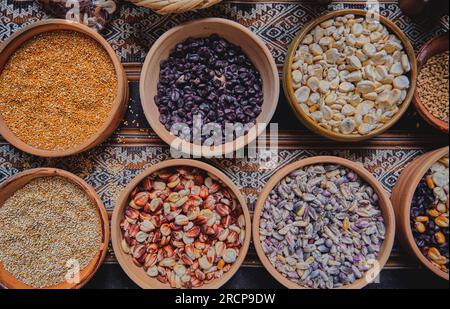 Varie spezie essiccate, cereali andini e cereali in piccole ciotole ed erbe crude, pagamento pachamama, cultura peruviana andina Foto Stock