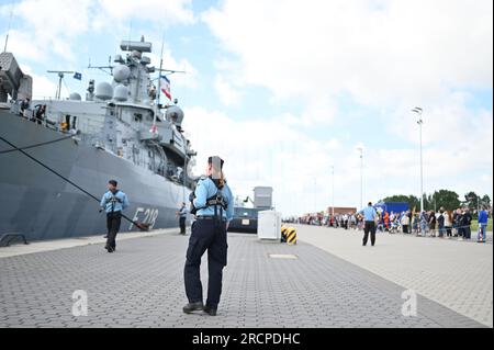 Wilhelmshaven, Germania. 16 luglio 2023. Una marina donna osserva l'attracco della fregata. La fregata "Meclemburgo-Vorpommern" ritorna dal dispiegamento NATO. Durante i suoi sei mesi di dispiegamento, la fregata è stata impegnata in esercitazioni multinazionali insieme all'unità portaerei della portaerei americana "USS Gerald Ford" nel Mare del Nord e nell'Artico. Crediti: Lars Penning/dpa/Alamy Live News Foto Stock