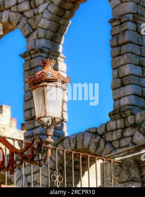 Segovia, Spagna - 11 febbraio 2023: Acquedotto romano. Vecchio lampione di fronte alle colonne in pietra dell'edificio medievale dell'acquedotto. Il posto famoso Foto Stock