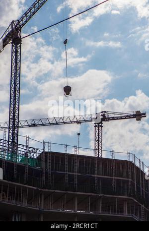 Gru che lavorano in un edificio residenziale. Cielo blu nuvoloso Foto Stock