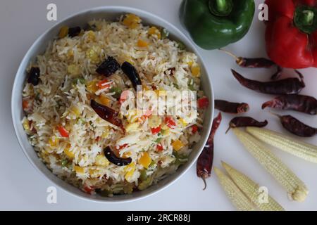 Riso vegetale freddo all'aglio. Riso basmati leggermente speziato all'aglio con peperone saltato e mais. Ripresa su sfondo bianco con r Foto Stock