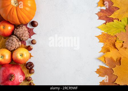 Cornice autunnale con foglie di acero giallo, noci, mele e zucca. Raccolta autunnale su sfondo grigio calcestruzzo con spazio di copia Foto Stock