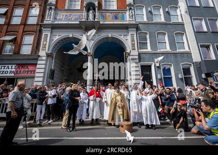 Londra, Regno Unito. 16 luglio 2023. I sacerdoti liberano le colombe all'esterno della chiesa italiana di San Pietro davanti alla Processione di nostra Signora del Carmelo, a partire dalla chiesa italiana di San Pietro e poi per le strade di Clerkenwell. I carri allegorici riportano raffigurazioni a grandezza naturale di scene bibliche in un festival cattolico romano che si svolge ogni anno dagli anni '1880 nella zona che un tempo era la piccola Italia della capitale. Crediti: Stephen Chung / Alamy Live News Foto Stock