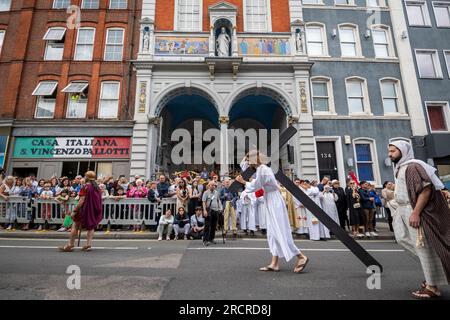 Londra, Regno Unito. 16 luglio 2023. Un uomo che interpreta Gesù che porta la croce passando davanti alla chiesa italiana di San Pietro durante la Processione della Madonna del Carmelo, partendo dalla chiesa italiana di San Pietro e poi per le strade di Clerkenwell. I carri allegorici riportano raffigurazioni a grandezza naturale di scene bibliche in un festival cattolico romano che si svolge ogni anno dagli anni '1880 nella zona che un tempo era la piccola Italia della capitale. Crediti: Stephen Chung / Alamy Live News Foto Stock