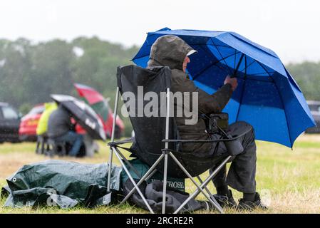 Fairford, Gloucestershire, Regno Unito. 16 luglio 2023. Gli appassionati di aviazione che guardavano lo spettacolo aereo Royal International Air Tattoo hanno dovuto affondare sotto qualche pioggia di passaggio durante l'evento Foto Stock