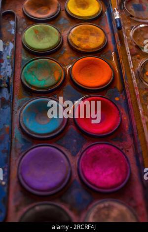 Set di vecchie vernici ad acquerello usate sfondo artistico ravvicinato. Uno degli strumenti grafici: Tavolozza dei colori sfondo scuro. Foto Stock