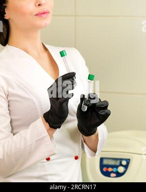 Infermiere che tiene le provette per l'analisi del sangue. Provetta per vuoto con gel eparinico per il prelievo ematico. Per la raccolta e la somministrazione di pla autologo Foto Stock