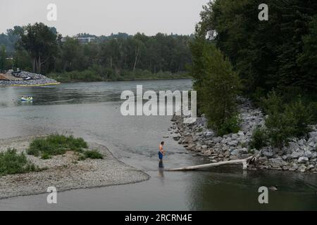 Calgary, Alberta, Canada. 15 luglio 2023. Un uomo nuota nel fiume di fronte al Prince Park, mentre il cielo è coperto di fumo da incendi, a Calgary, Canada. (Immagine di credito: © Matias Basualdo/ZUMA Press Wire) SOLO USO EDITORIALE! Non per USO commerciale! Foto Stock