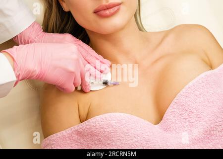 Decollare l'iniezione di mesoterapia per ringiovanimento dell'area per pazienti di sesso femminile. Trattamento anti-età in clinica cosmetologica. Mano dell'estetista nei guanti con syr Foto Stock