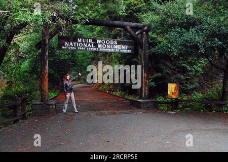 Una giovane donna posa di fronte all'ingresso del Muir Woods National Monument in California, vicino a San Francisco Foto Stock