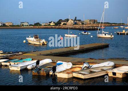 Piccoli gommoni fiancheggiano un molo in un porto calmo in una soleggiata giornata estiva Foto Stock