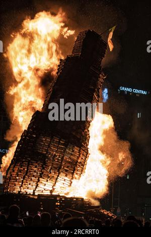 11 luglio 2023, Belfast, Irlanda: Il falò a Sandy Row inizia a cadere dopo meno di tre minuti di incendio. Le pire, costruite con pallet di legno e talvolta pneumatici e altri materiali, sono costruite in tutta l'Irlanda del Nord nei quartieri protestanti per l'annuale 11 luglio, o celebrazioni dell'undicesima notte per commemorare la conquista guglielamita degli anni '1690, che ha dato inizio all'ascendenza protestante in Irlanda. Le pire sono generalmente adornate con il tricolore irlandese e altre regalia o simboli associati al nazionalismo irlandese e all'identità come provocazione verso il commun cattolico Foto Stock