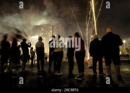 11 luglio 2023, Belfast, Irlanda: Uno spettacolo di fuochi d'artificio intrattiene le folle che si sono riunite per guardare il falò a Sandy Row a Belfast City, che è previsto per essere acceso a mezzanotte. Le pire, costruite con pallet di legno e talvolta pneumatici e altri materiali, sono costruite in tutta l'Irlanda del Nord nei quartieri protestanti per l'annuale 11 luglio, o celebrazioni dell'undicesima notte per commemorare la conquista guglielamita degli anni '1690, che ha dato inizio all'ascendenza protestante in Irlanda. Le pire sono generalmente adornate con il tricolore irlandese e altre regalia o simboli associati W. Foto Stock