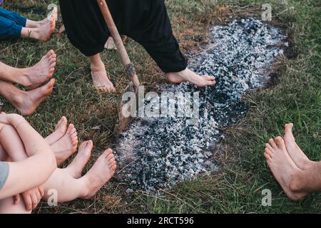 Camminata sul carbone o cammina sul fuoco. Persona scalza su legno bruciato e braci calde. Allenare la forza di volontà e la forza per la guarigione. iniziazione e fede Foto Stock