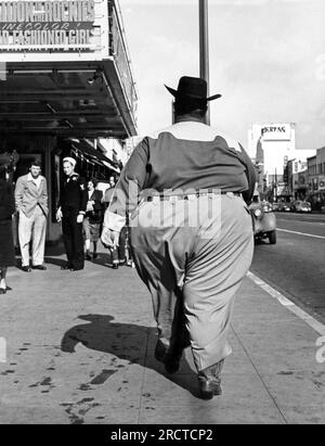 Chicago, Illinois: 1949. Il dorso di un uomo molto grande che indossa un cowboy che cammina per una strada urbana. Foto Stock