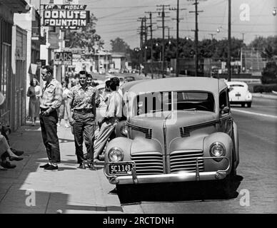 California: 1953. Adolescenti e giovani adulti che si trovano sulla strada fuori dal negozio di fontane. Foto Stock