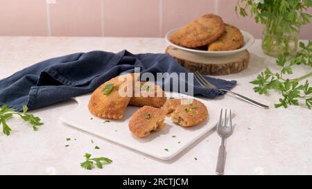 Polpettine di carne e foglie di prezzemolo su piatti di ceramica bianca in una cucina da banco. Foto Stock