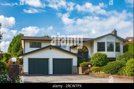 Garage doppio con breve vialetto in una soleggiata giornata estiva. Un quartiere perfetto. Casa per famiglie con ampia porta del garage e vialetto di cemento davanti. A Foto Stock