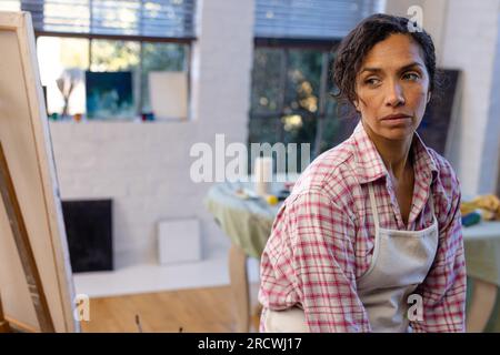 Donna birazziale che indossa grembiule nello studio di casa Foto Stock