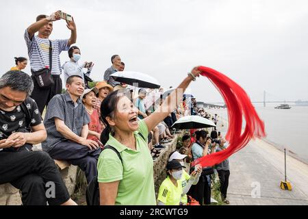 Wuhan, Cina. 16 luglio 2023. Gli spettatori fanno il tifo sulla riva del fiume Yangtze mentre guardano l'azione durante il 48° Wuhan International Yangtze River Crossing Festival. Più di 2.000 partecipanti partecipano al 48° Festival Internazionale di attraversamento del fiume Yangtze nella città di Wuhan, nella provincia di Hubei della Cina centrale. Questo evento sportivo, che si tiene ogni anno, segna la nuotata del presidente Mao Zedong sul fiume Yangtze a Wuhan il 16 luglio 1966. Credito: SOPA Images Limited/Alamy Live News Foto Stock