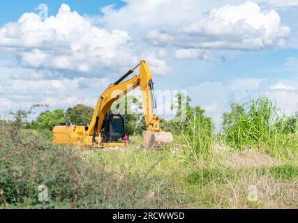 Escavatore che esegue lo scavo per regolare il livello del suolo nei cantieri edili. Foto Stock