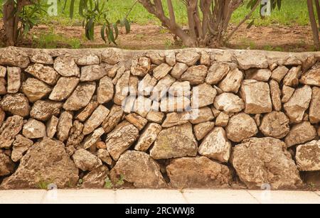 muro di mattoni di supporto in pietra in spagna lungo un marciapiede Foto Stock