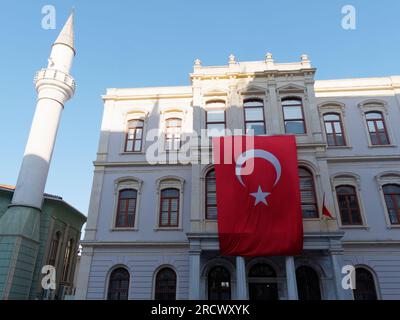 Edificio con una bandiera turca appesa sul davanti e un minareto a sinistra, Istanbul, Turchia Foto Stock