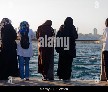 Gruppo di donne musulmane goditi il sole estivo che tramonta sul Mare del Bosforo da Uskudar sul lato asiatico di Istanbul, Turchia Foto Stock