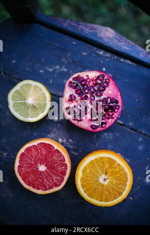 Lime, melograno, rosso e arancio naturale sulla sedia rustica. Foto Stock