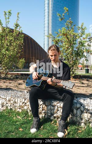 uomo bianco che suona la chitarra fuori di fronte allo skyscreaper Foto Stock