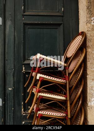 Sedie da bistrot francesi incantevoli impilate su un edificio Foto Stock