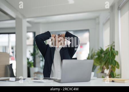 Concetto di sovraccarico e scadenza. Stressato uomo d'affari asiatico che lavora su laptop, toccando e massaggiando templi. Maschio maturo con mal di testa, riducendo Foto Stock