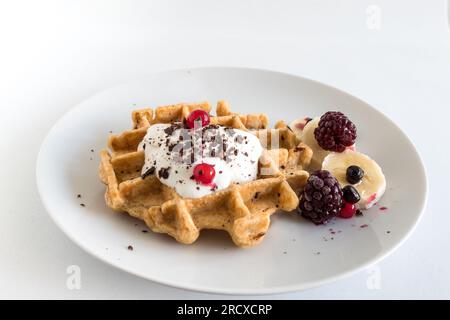 Deliziosi waffle di farinata d'avena fatti in casa con cremoso yogurt naturale, miele, banana, mirtilli, lamponi e cioccolato tritato Foto Stock