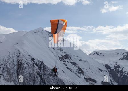 Gudauri, Georgia - 1° maggio 2019: Parapendio in volo di fronte alle cime innevate del Caucaso in una giornata di sole Foto Stock