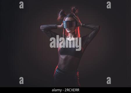Ritratto di una bella donna cyber model che indossa occhiali futuristici sulla testa con luce al neon in un ambiente tecnologico virtuale Foto Stock