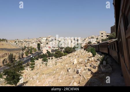 Amman, Giordania (un treno tra le case) un vecchio treno turco a vapore ottomano in Giordania - Hedjaz Jordan Railway Foto Stock