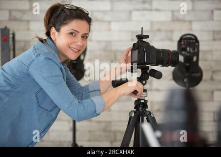 fotografa donna che imposta la fotocamera sul cavalletto Foto Stock