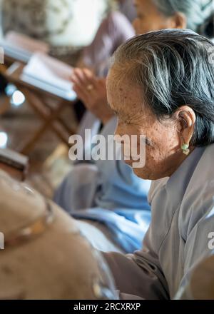 Una donna anziana che indossa orecchini di giada adora la pagoda buddista Ling Ung Bai Buc a Son tra, Danang, Vietnam. Foto Stock